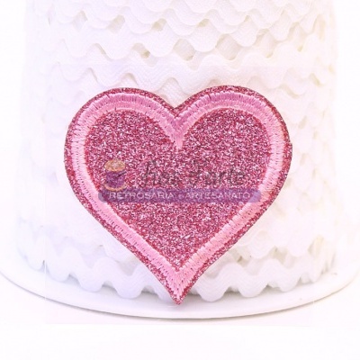 Adesivo cor-de-rosa brilhante em forma de coração sobre fundo branco texturizado.