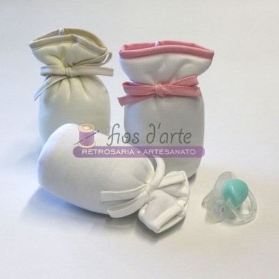 Produtos para bebé em tecido branco com laços e chupeta azul