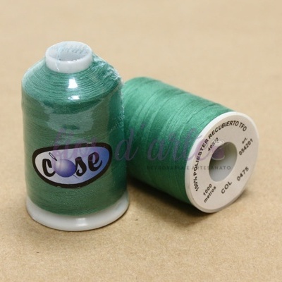 Dois carretéis de linha de costura verdes sobre mesa castanha