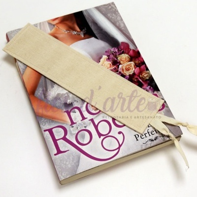 Marca páginas de tecido bege sobre revista com mulher vestida de noiva e bouquet colorido