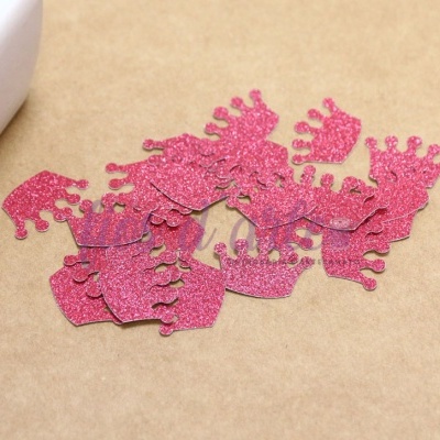 Decorações pequenas em forma de coroa rosa brilhante sobre mesa castanha