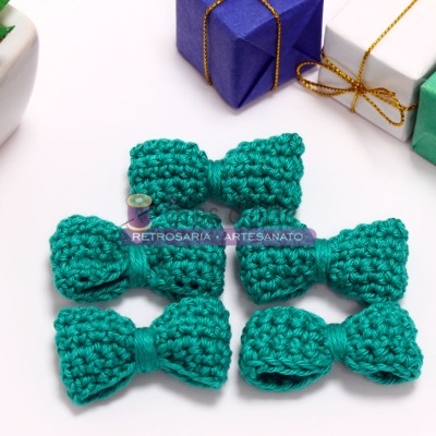 Seis laços de croché verdes com caixas de presente coloridas e planta suculenta em fundo branco