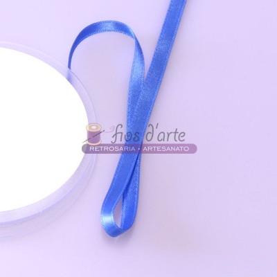 Fita azul de cetim ao lado de carretel branco sobre fundo lilás