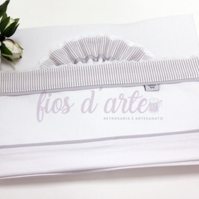 Protetor de berço branco com detalhes cinza claro e flores brancas ao lado