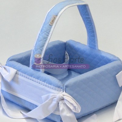 Cesto de bebê azul claro acolchoado com alça e laços brancos.