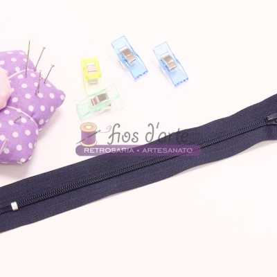 Fecho éclair azul escuro com alfineteiro e clipes coloridos ao fundo