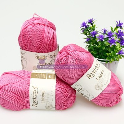 Três novelos de lã rosa Rosários4 Lisboa com flores roxas em vaso