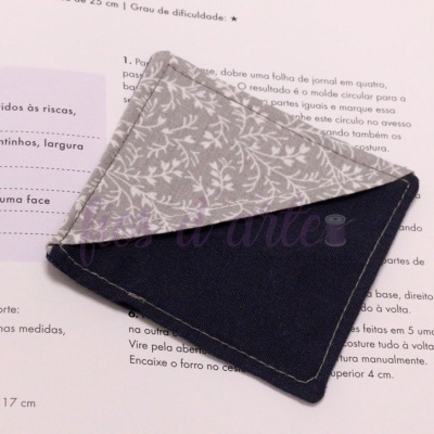 Panos de loiça com padrão floral cinza e tecido azul escuro sobre livro aberto