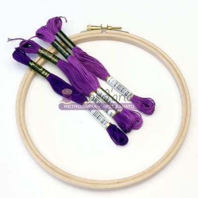 Moldura de bordado em madeira com novelos de linha roxa sobre fundo branco
