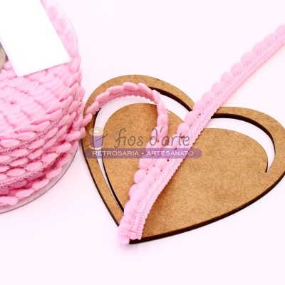 Rolo de fita rosa com pompons sobre suporte em forma de coração