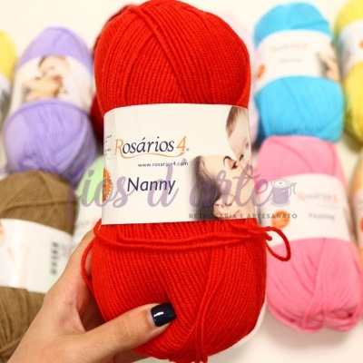Novelo de lã acrílica vermelho Rosários 4 Nanny com fundo de vários novelos coloridos