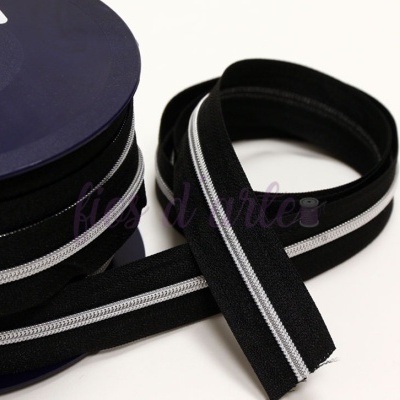 fita zíper preta com faixa refletora branca enrolada sobre superfície branca