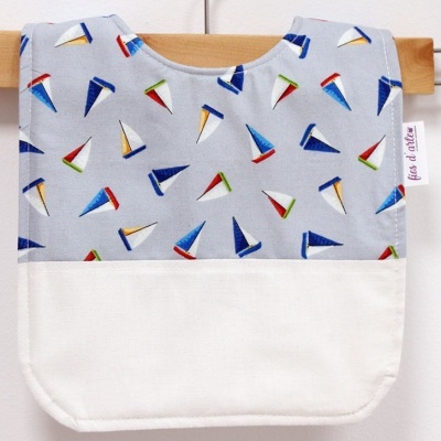 Babete de tecido com padrão de barcos coloridos e parte inferior branca