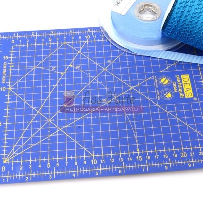 Tapete de corte azul com marcações e texto amarelo em fundo branco, com fitas azuis no canto superior direito.