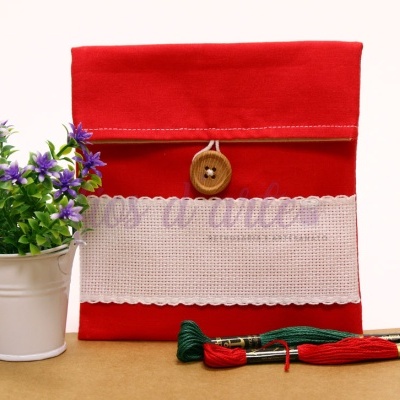 Bolsa vermelha com botão e faixa branca, vaso com flores lilases, meadas de linha verde e vermelha