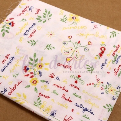 Pano branco bordado com flores, pássaros e palavras coloridas em português