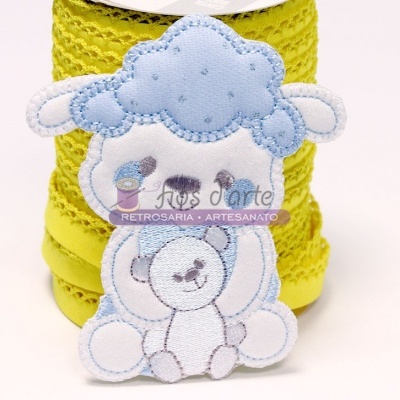 Figura de ovelha bordada em tecido azul e branco com fita amarela atrás
