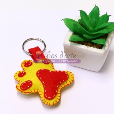 Porta-chaves de feltro em forma de pata amarela e vermelha ao lado de uma planta artificial em vaso branco