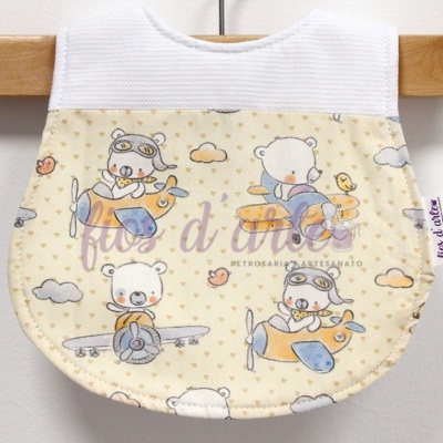 Babete de bebé creme e branco com padrão de ursos em aviões.