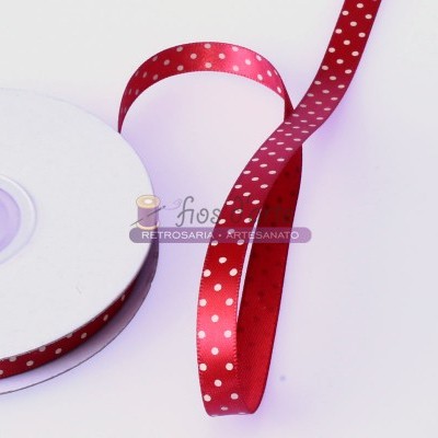 Fita de cetim vermelha com bolinhas brancas enrolada numa bobina branca