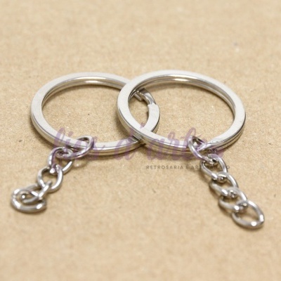 Dois anéis prateados com corrente numa superfície castanha lisa