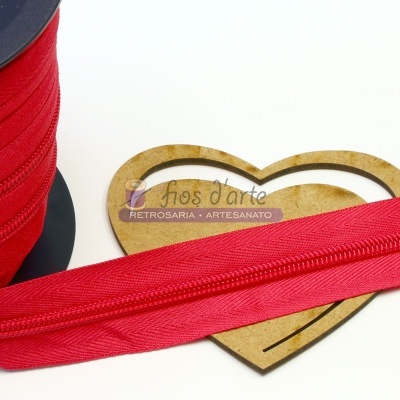 Fita vermelha de tecido com fecho éclair sobre suporte em forma de coração de madeira