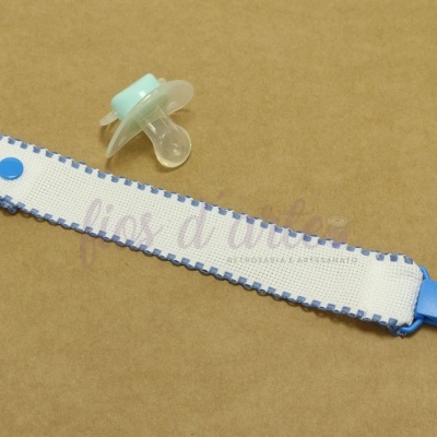 Chupeta com fita branca e azul sobre fundo castanho