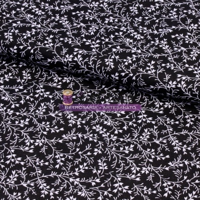 Tecido preto com padrão branco de ramos e folhas e etiqueta roxa com texto