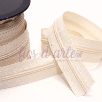 Fita elástica bege enrolada num carretel preto e parte solta