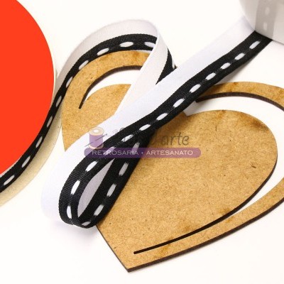 Fita preta com pontos brancos sobre base em forma de coração de madeira clara
