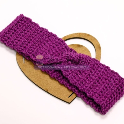 Faixa de cabelo roxa em croché sobre suporte de madeira em forma de coração
