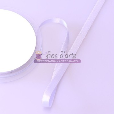 Fita de cetim branca com bobina e selo 'fios d'arte' sobre fundo lilás