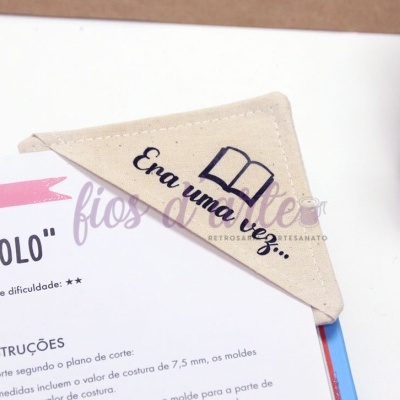 Marcador de página de tecido bege com texto bordado e imagem de livro