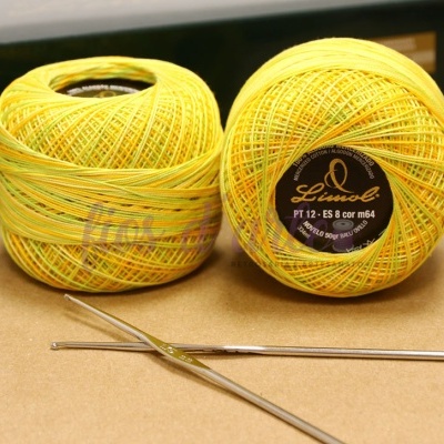 Novelos de linha para crochet amarelos e verdes com etiquetas e duas agulhas metálicas.