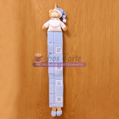 Régua de crescimento de tecido azul com ursinho de pelúcia pendurada na parede