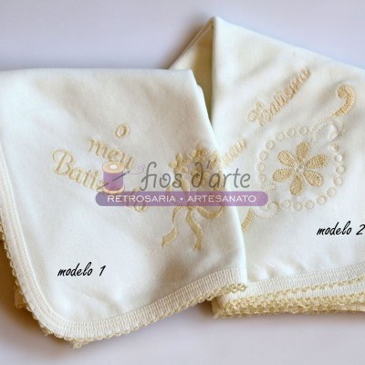 Duas mantas de bebé brancas, uma com bordado 'o meu Batizado' e outra com bordado floral creme, acabamento em renda