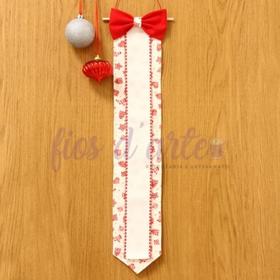 Fita decorativa branca com padrão vermelho e laço vermelho pendurada em madeira