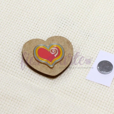 Alfinete de madeira em forma de coração colorido sobre tecido bege