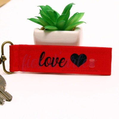 Chaveiro vermelho com palavra 'love' e coração preto junto a chaves e planta em vaso branco