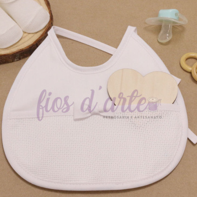 Babete branco com bolso texturizado, chupeta verde-água, anéis de madeira e meias brancas