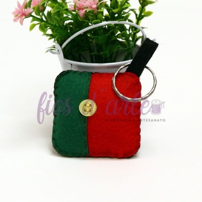 Porta-chaves tecido verde e vermelho com botão e argola metálica junto a vaso com flores