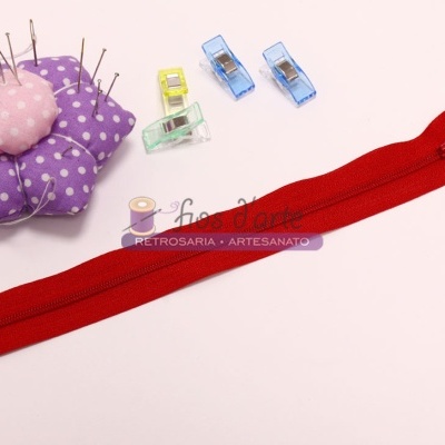 Fecho éclair vermelho com acessórios de costura coloridos sobre fundo branco
