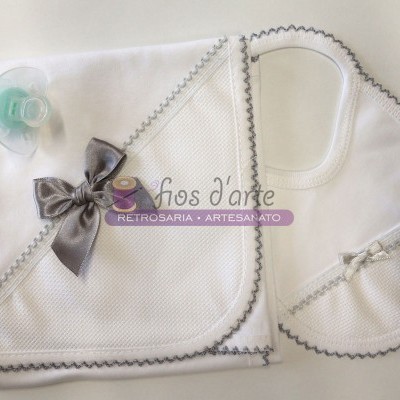 Conjunto de manta, toalha com capuz e babete branco com bordado cinza e um laço cinza, e uma chupeta verde claro