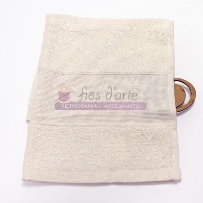 Toalha de banho bege com pega de madeira e etiqueta com texto em fundo branco