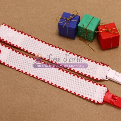 Dois clips para chupeta brancos com detalhes vermelhos junto a três pequenas caixas coloridas