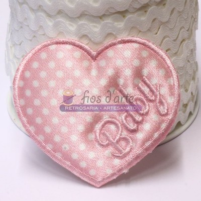 Aplicação de tecido em forma de coração rosa com bolinhas brancas e palavra 'Baby' bordada