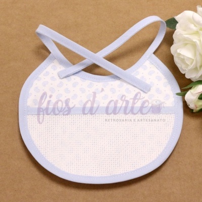 Babete de bebé branco com padrão azul claro e fitas para atar, com flores brancas ao lado