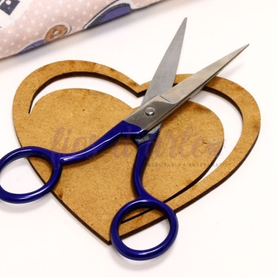 Tesoura pequena azul sobre suporte em forma de coração de madeira