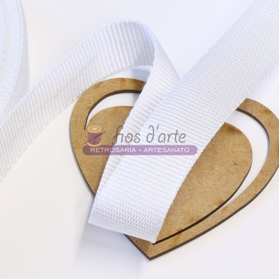 Fita branca de tecido sobre base de madeira em forma de coração com texto artesanal