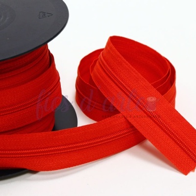 Rolo de fecho éclair vermelho em carretel preto com uma parte solta